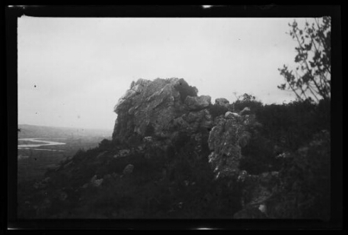 Gros rocher fragilisé par l'érosion surplombant un paysage (Finistère)